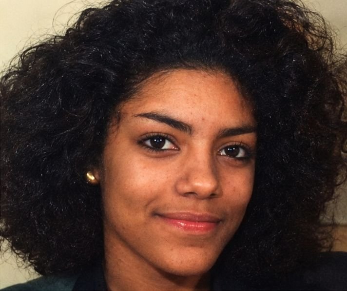 Cassandra Rhines smiling, with dark curly hair and a gold earring
