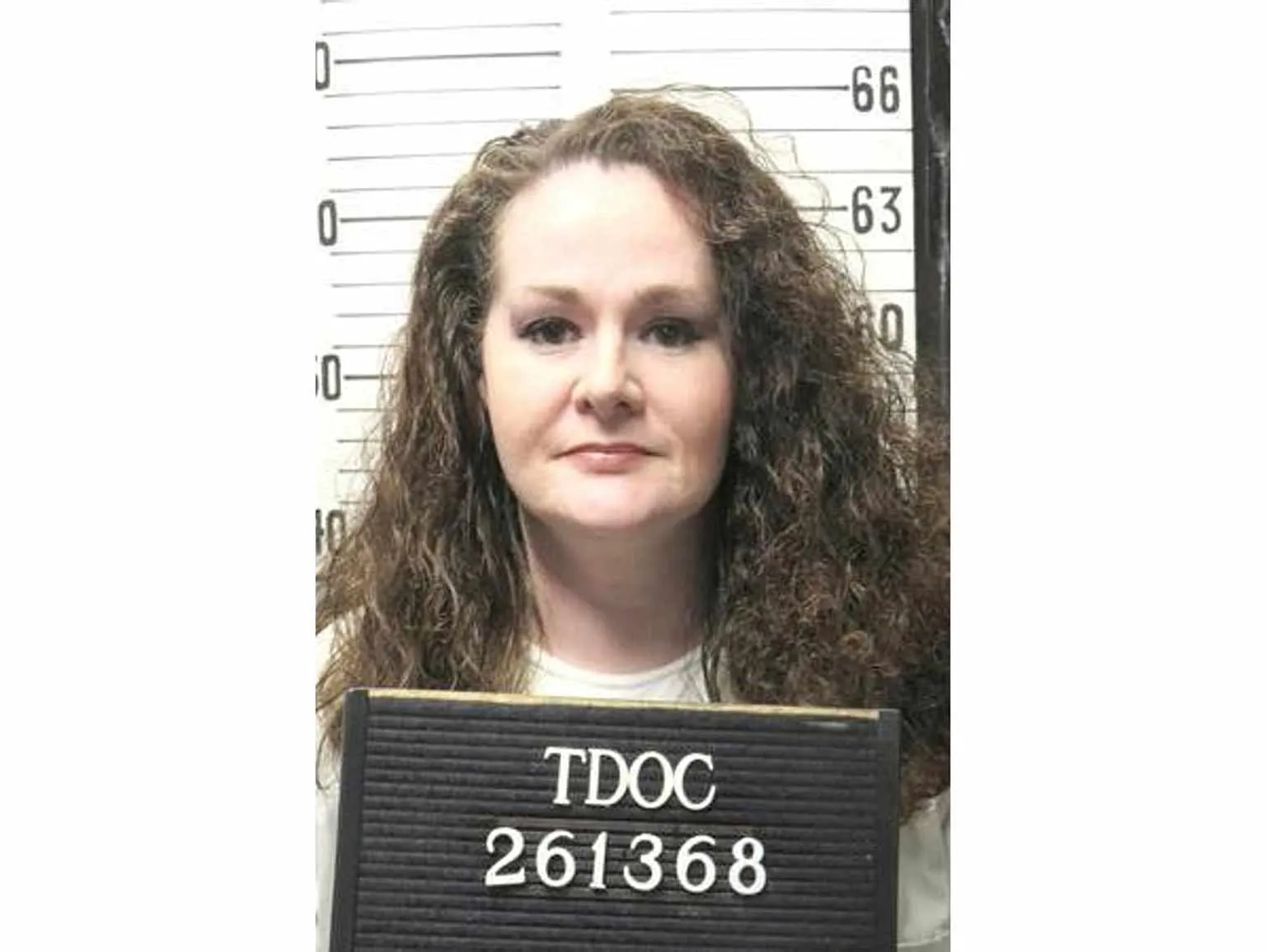 Christa Pike holding a Tennessee Department of Correction booking board