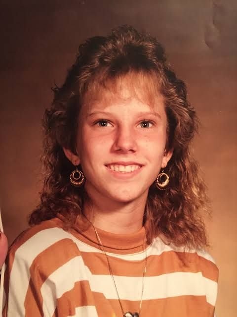 Colleen Slemmer as a smiling teenager in a striped shirt, in a school portrait