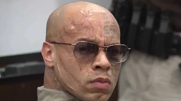 Nikko Jenkins in a courtroom, wearing tinted glasses, with tattoos across his face and head