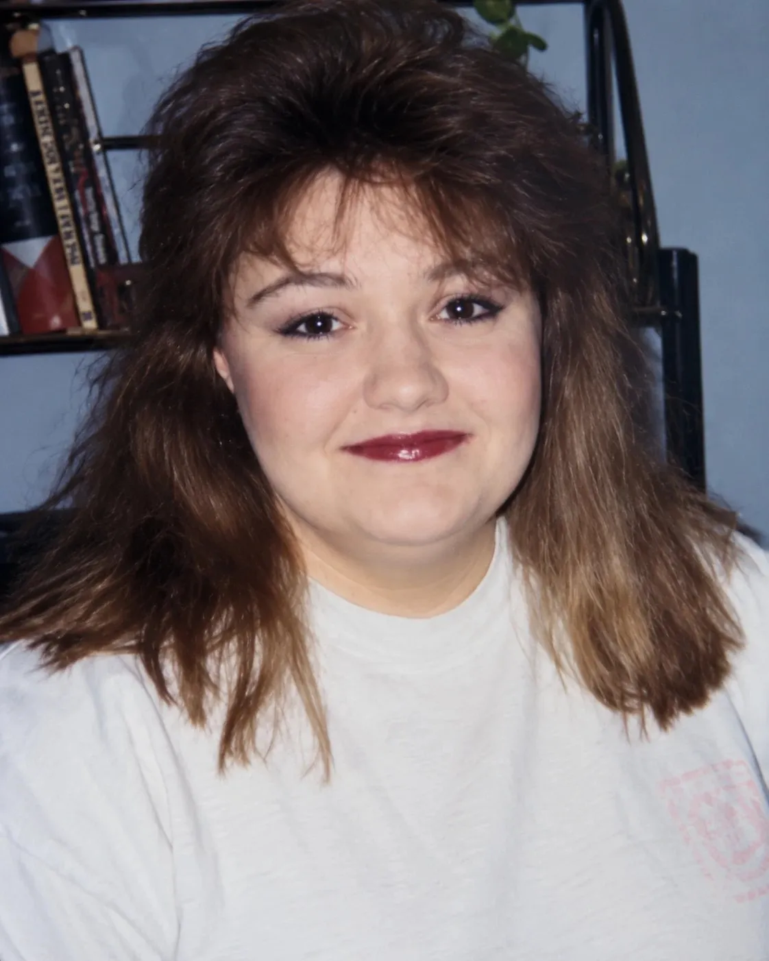 Mary K. Ross with long feathered hair and red lipstick, smiling slightly