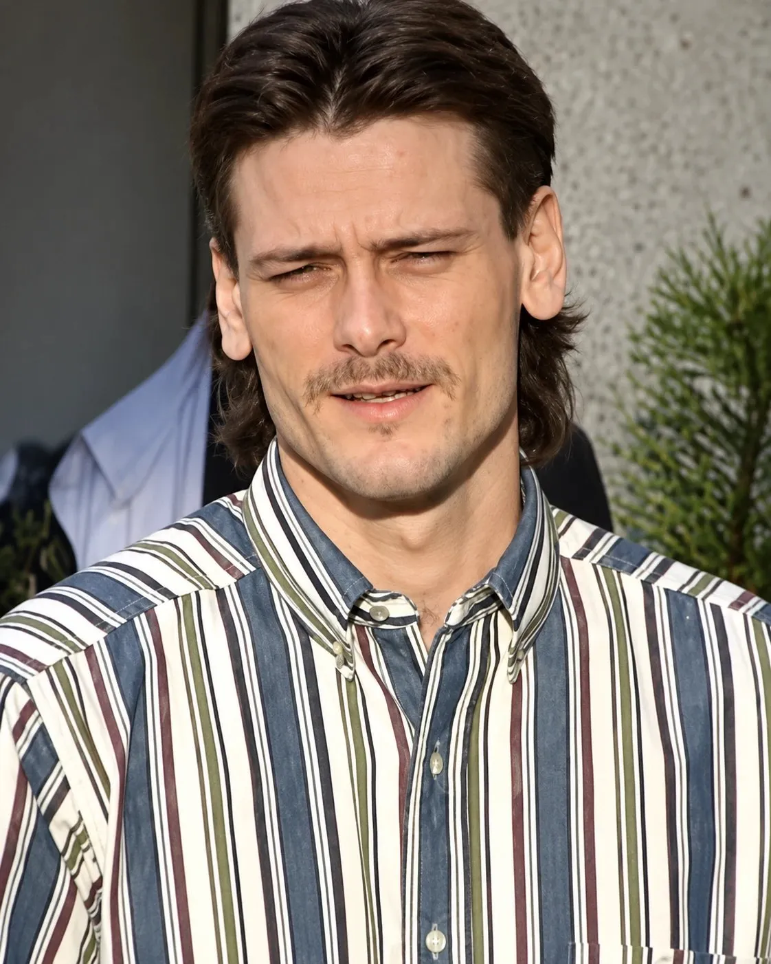 Michael Lee Smith as a young man with a mustache, in a striped shirt