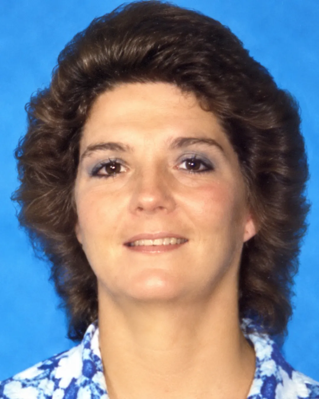 Pamela Dunn, with brown hair, against a blue background