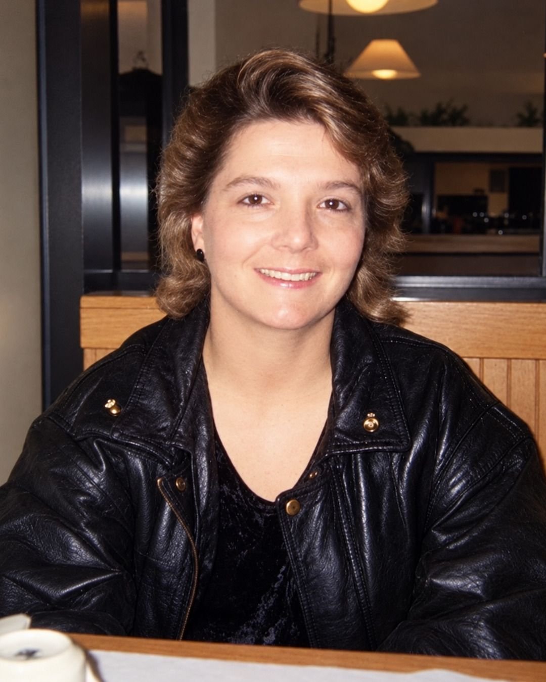 Pamela Dunn, smiling, in a black leather jacket at a restaurant table