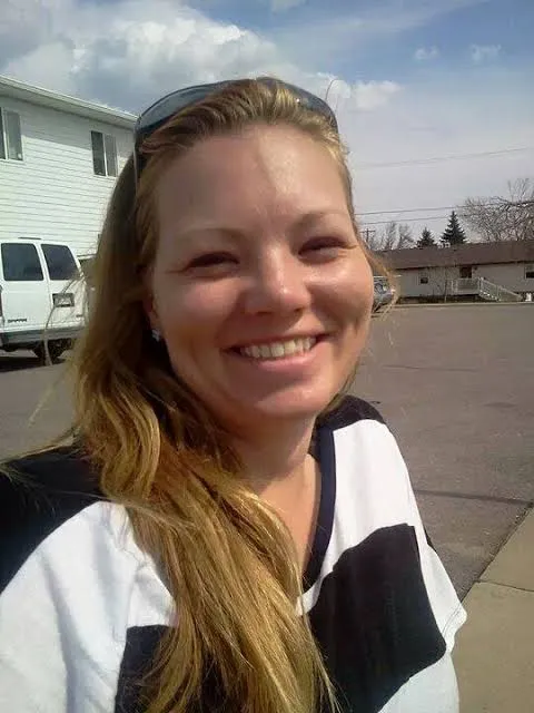 Rachel Cyriacks smiling outdoors in a parking lot, sunglasses on her head, wearing a black and white striped shirt