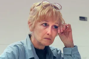 Margaret Rudin with her glasses pushed up on her head, resting her hand on her forehead